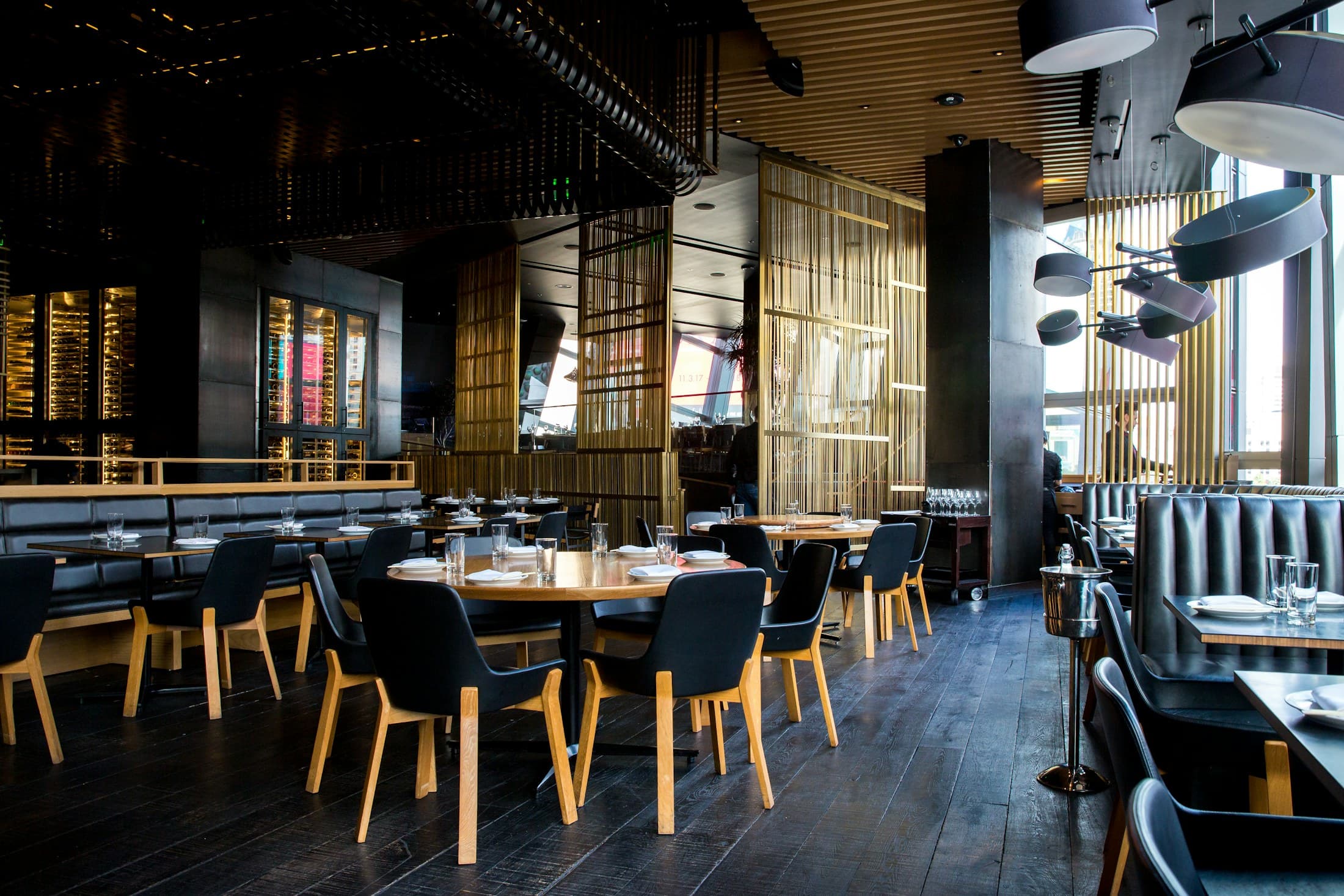 The main dining room set for evening service, dark wood chairs around round tables.