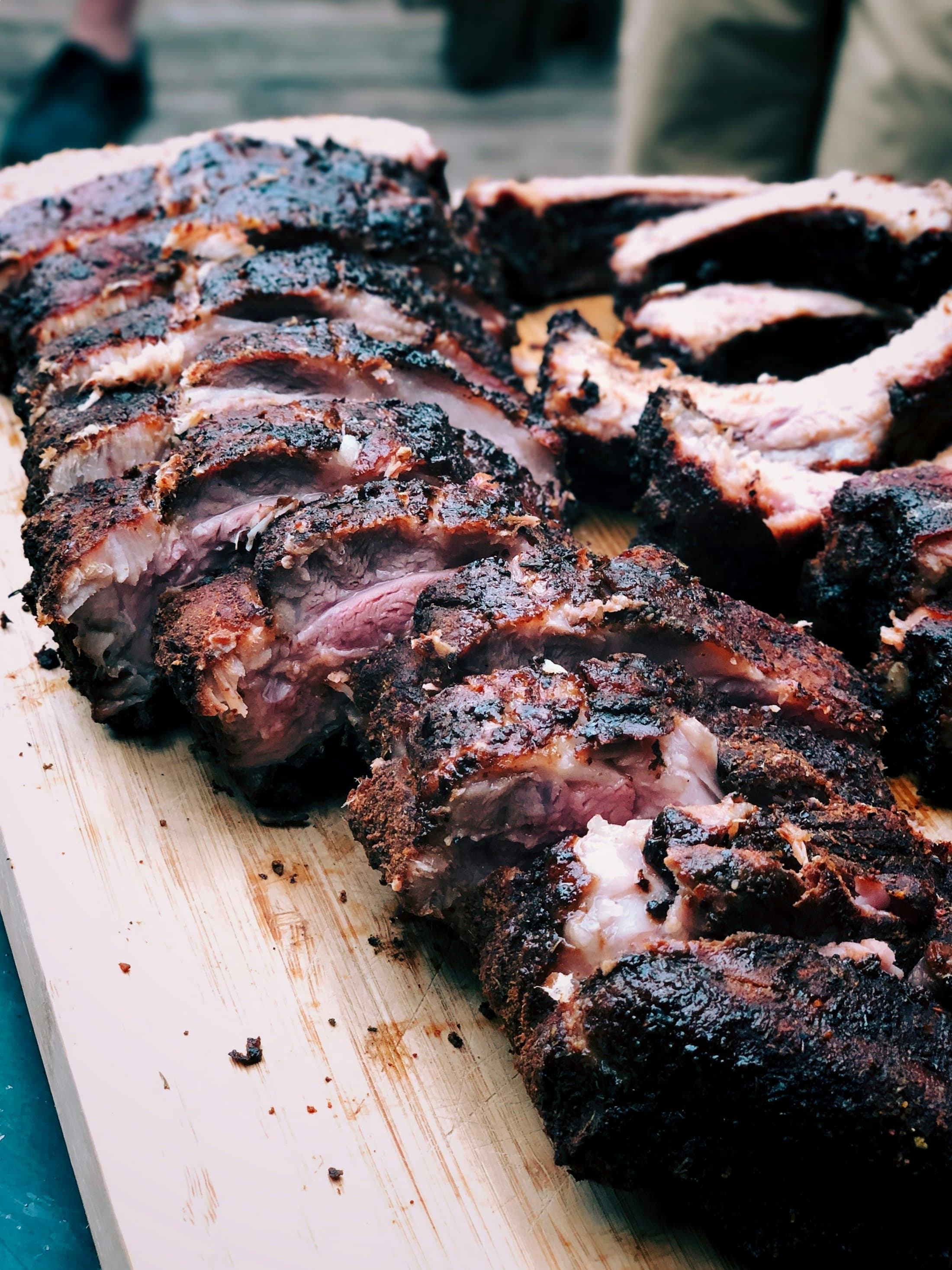 Beef ribs with a dark charcoal crust resting on a board.