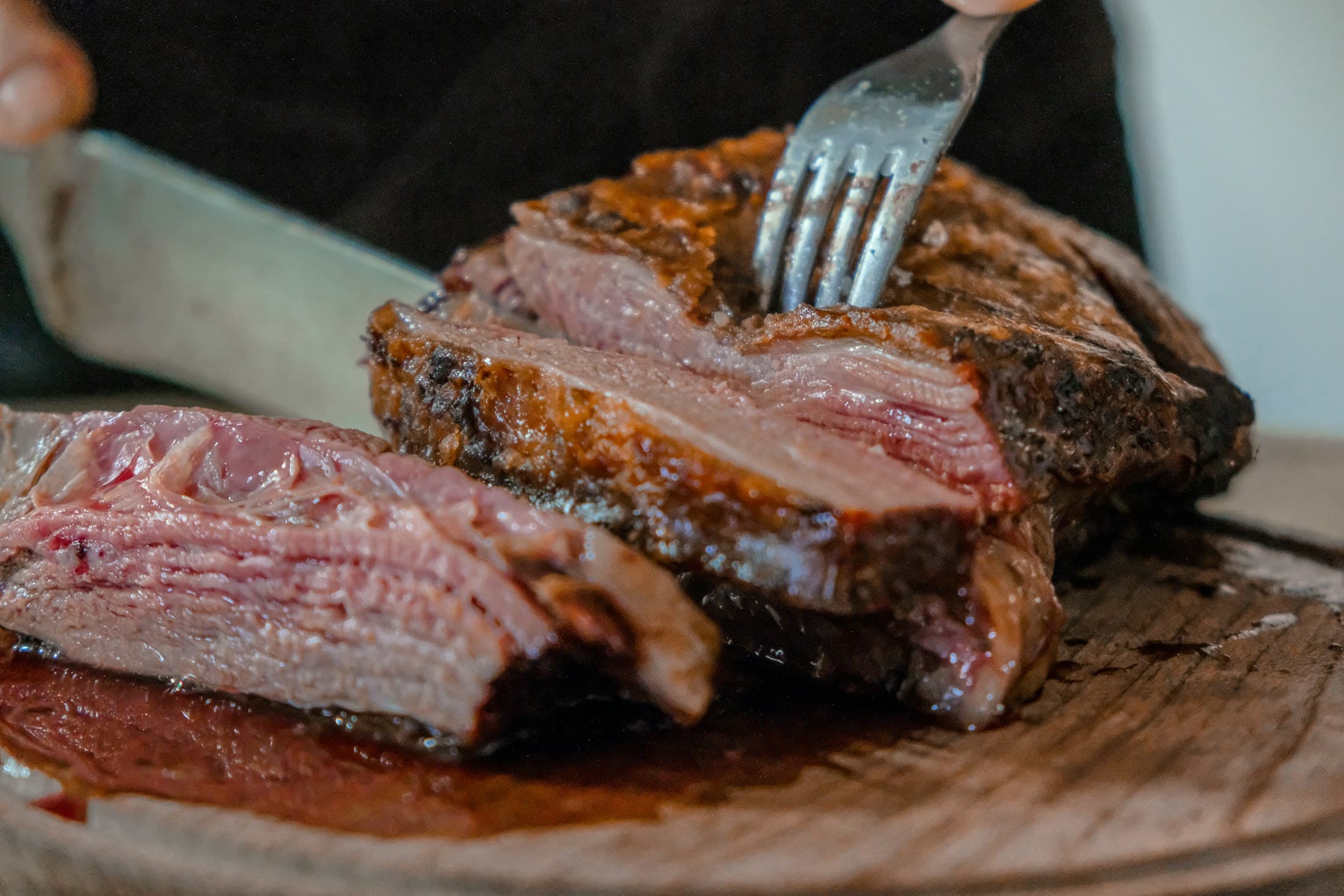 A fork lifting a slice of grilled beef from the board.